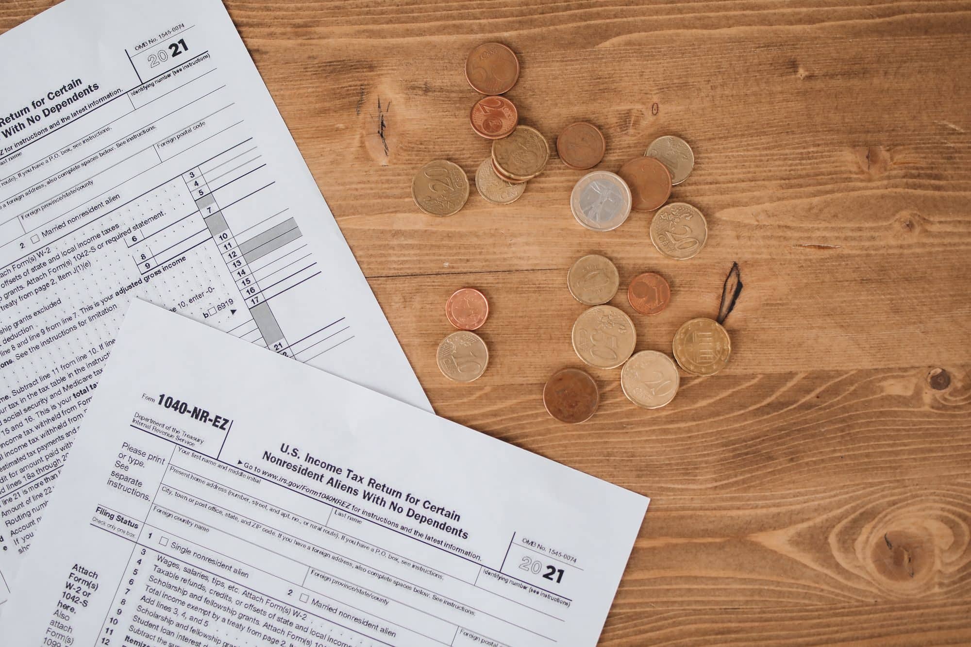 U.S. tax return forms and a scatter of coins on a wooden table
