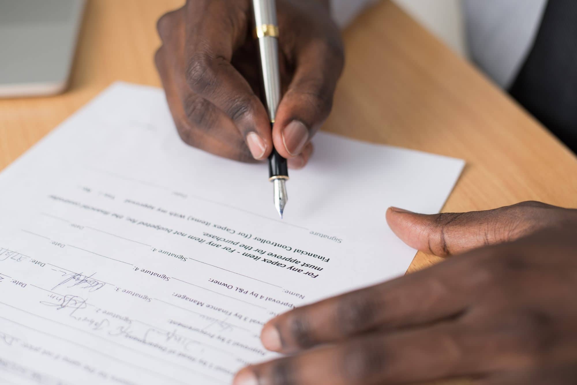 A hand fills out a paper form with a fountain pen