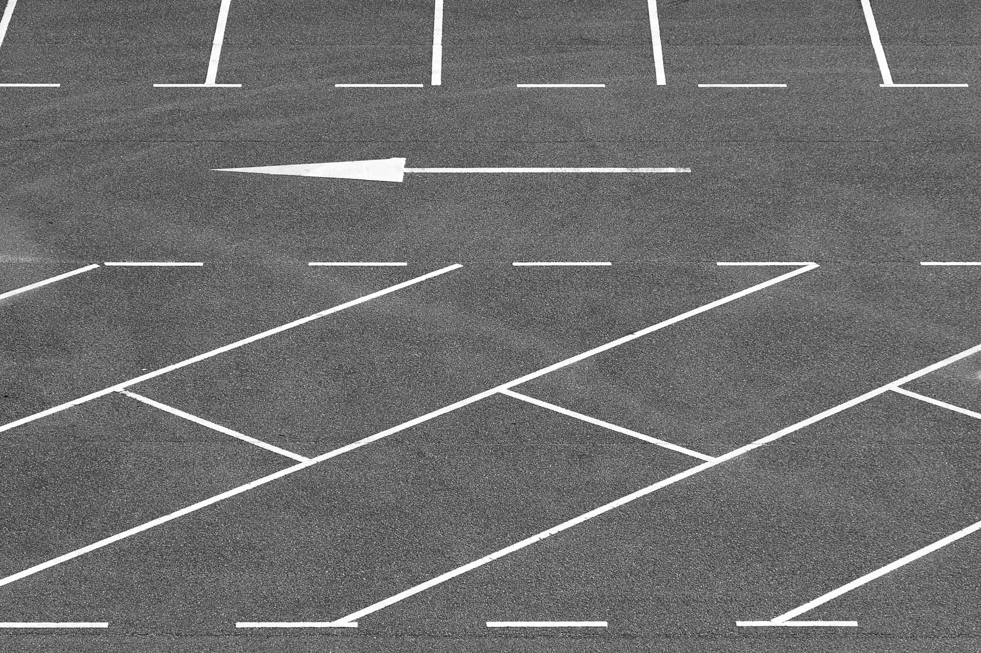 White parking stall lines and a directional arrow on an empty gray parking lot