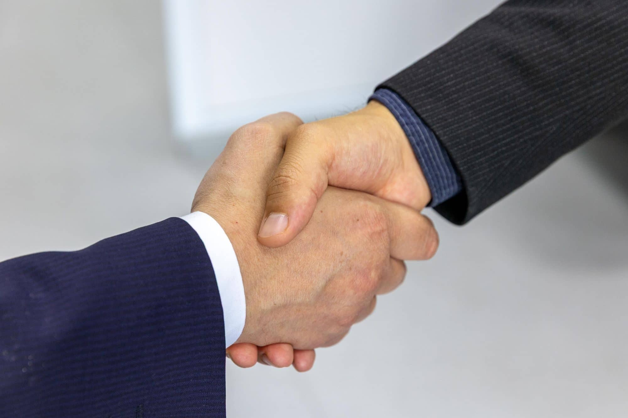 Two people in business jackets shake hands