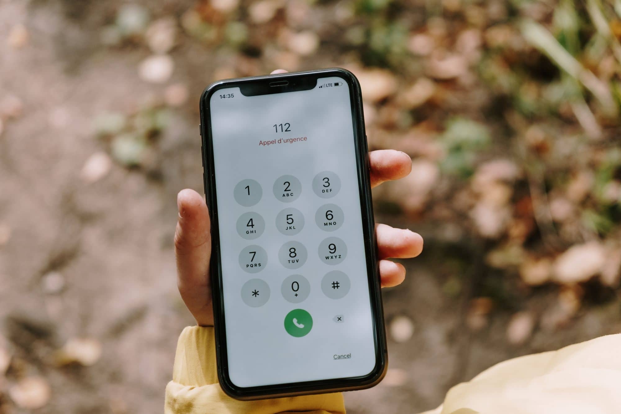 A hand holds a smartphone with the phone keypad open